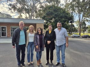 Five people stand in a line smiling