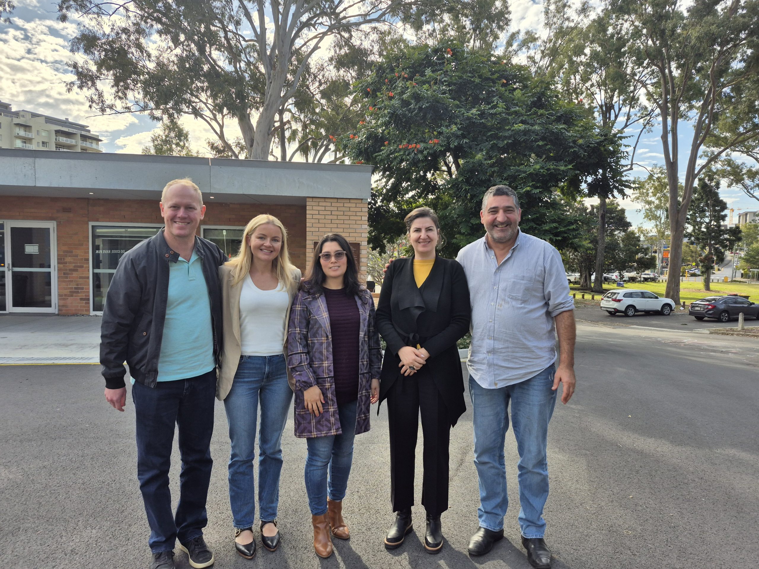 Five people stand in a line smiling