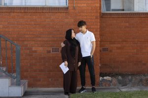 Latifa, an employee of Australia Post, standing in her front yard hugging her son Basir.